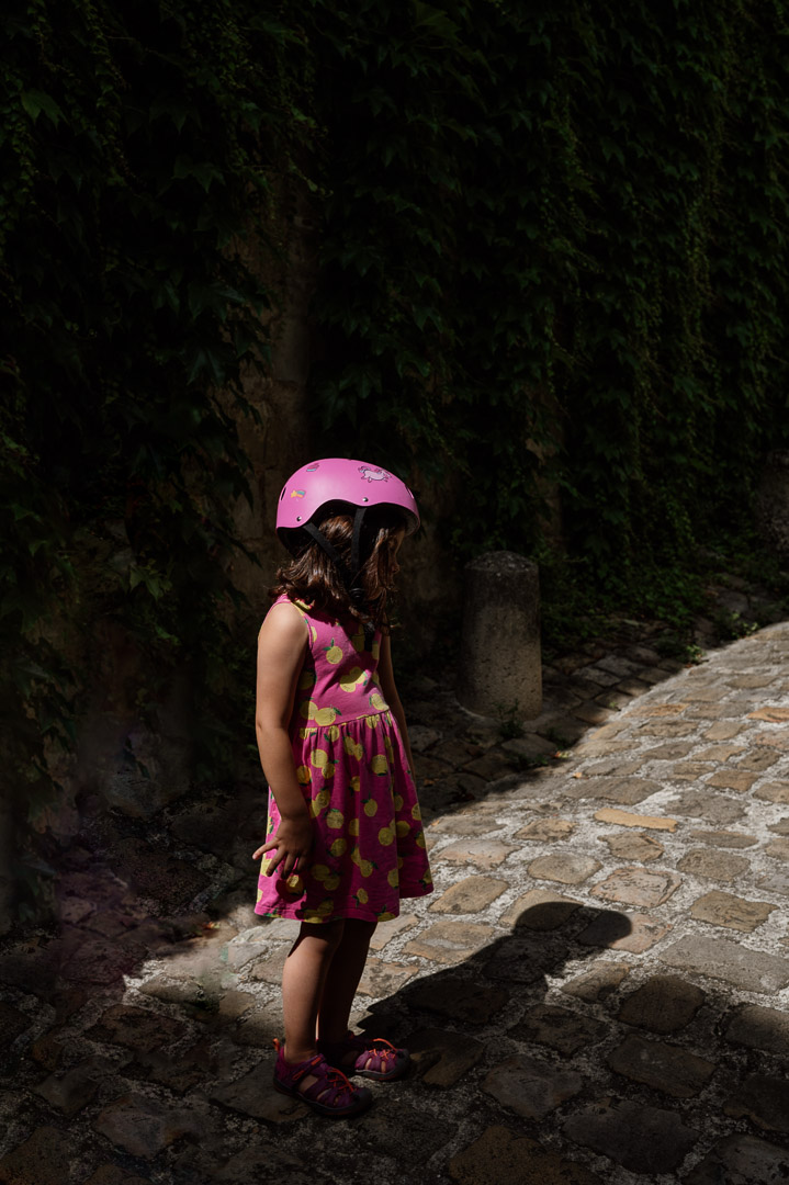 Kind mit Helm steht in der Sonne mit Schatten