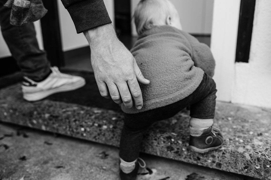 Baby wird mit Hand beim Treppensteigen geholfen