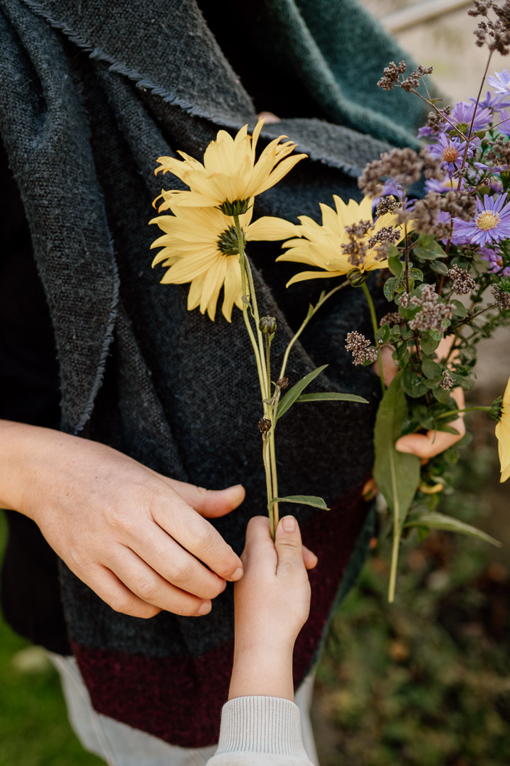 Kinderhand reicht Blumen an Erwachsene