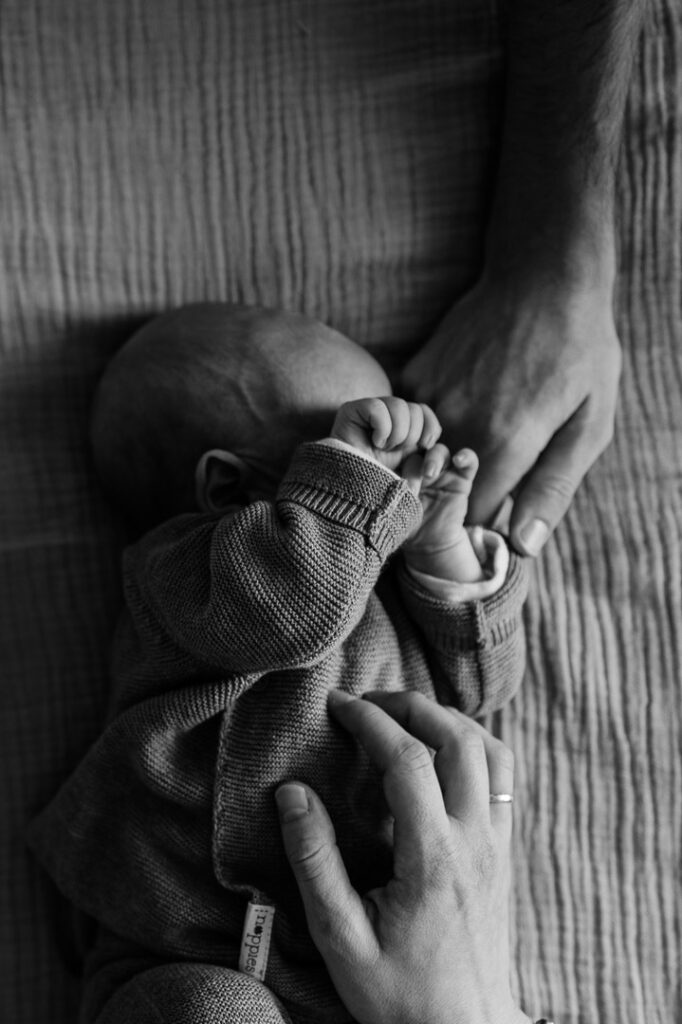 Liegendes Baby wird von Händen gestreichelt