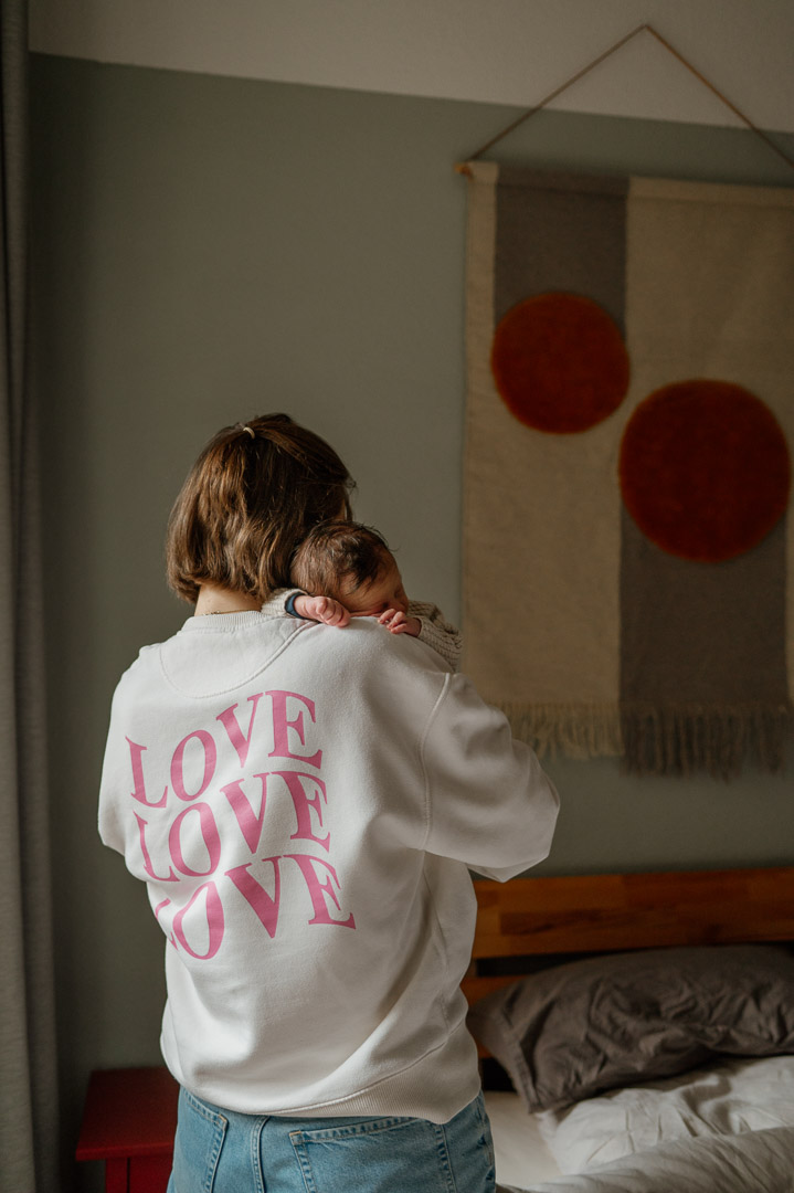 Mama trägt einen Pullover mit den Worten Love und hält Baby