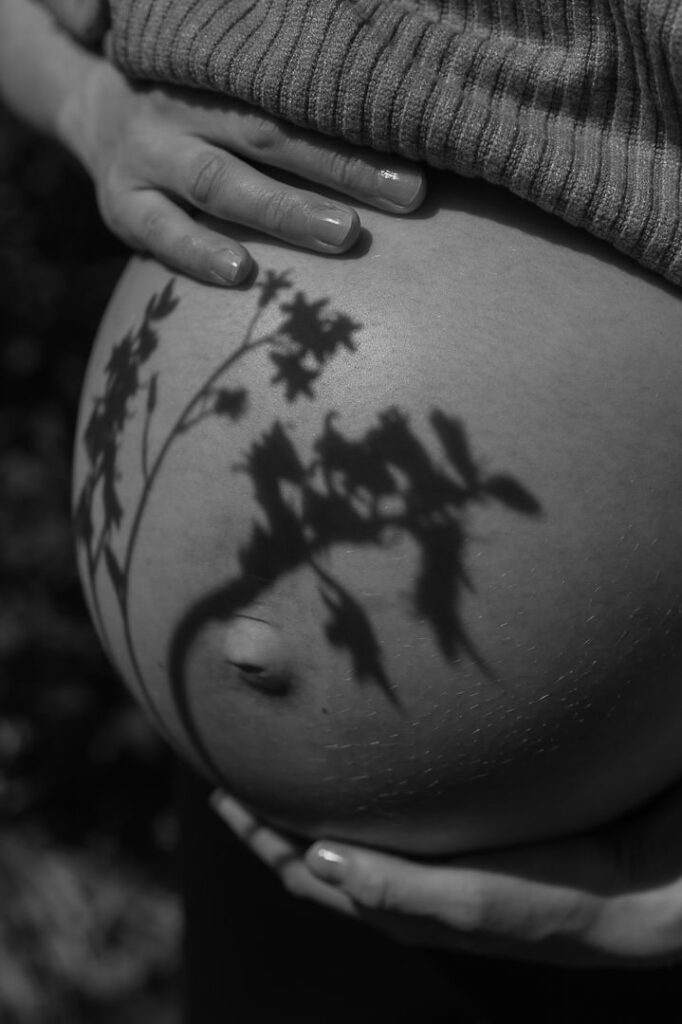 Schatten einer Blume auf Babybauch