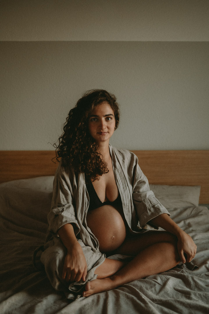 Schwangere sitzt auf dem Bett